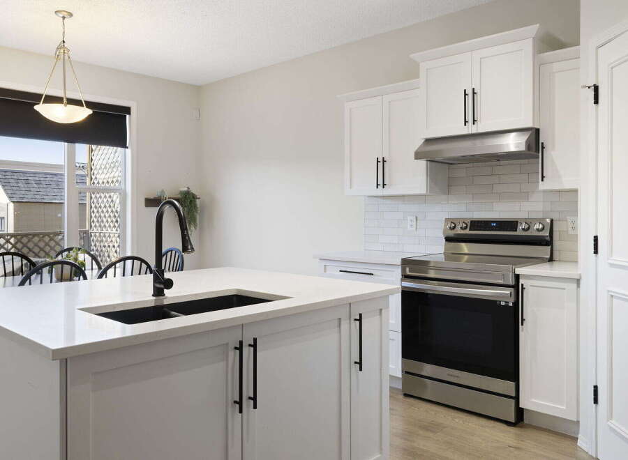 This stunning kitchen boasts a modern design with sleek white cabinetry and a spacious island, perfect for both cooking and entertaining.