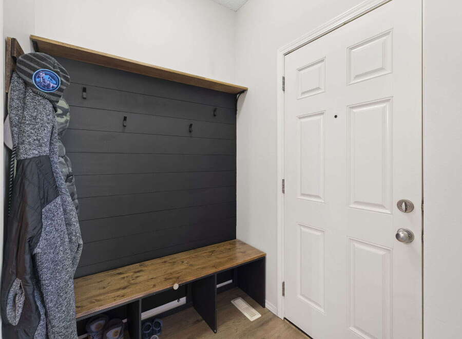 This entryway features a stylish and functional mudroom bench with a built-in shelf and coat hooks, perfect for organizing your belongings.