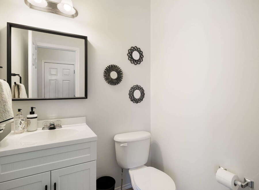 This stylish bathroom features a modern vanity with a sleek white countertop and a framed mirror.