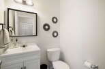 This stylish bathroom features a modern vanity with a sleek white countertop and a framed mirror.