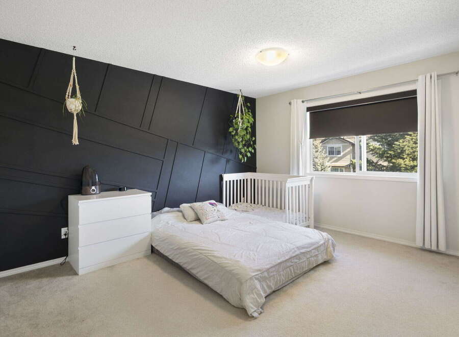 This stunning bedroom features a modern design with a striking black accent wall.