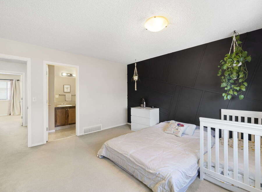 This charming bedroom features a modern design with a striking black accent wall.
