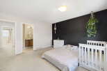 This charming bedroom features a modern design with a striking black accent wall.