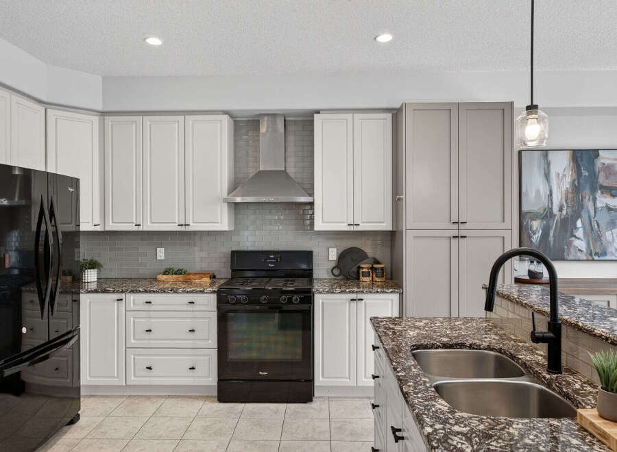 This stunning kitchen boasts modern elegance with its sleek black appliances and pristine white cabinetry.
