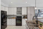 This stunning kitchen boasts modern elegance with its sleek black appliances and pristine white cabinetry.