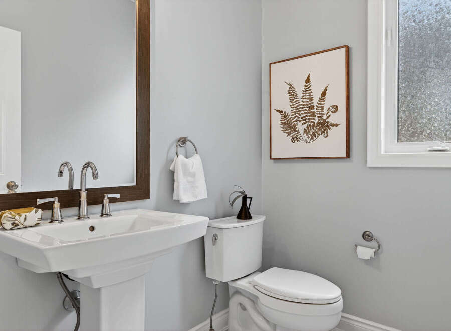 This stunning bathroom features a modern pedestal sink, a sleek toilet, and a beautiful framed artwork.