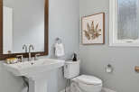 This stunning bathroom features a modern pedestal sink, a sleek toilet, and a beautiful framed artwork.