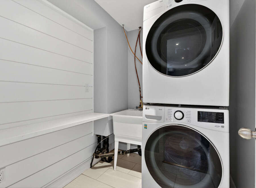 This stunning laundry room boasts a modern design with a stacked LG washer and dryer, maximizing space and efficiency.