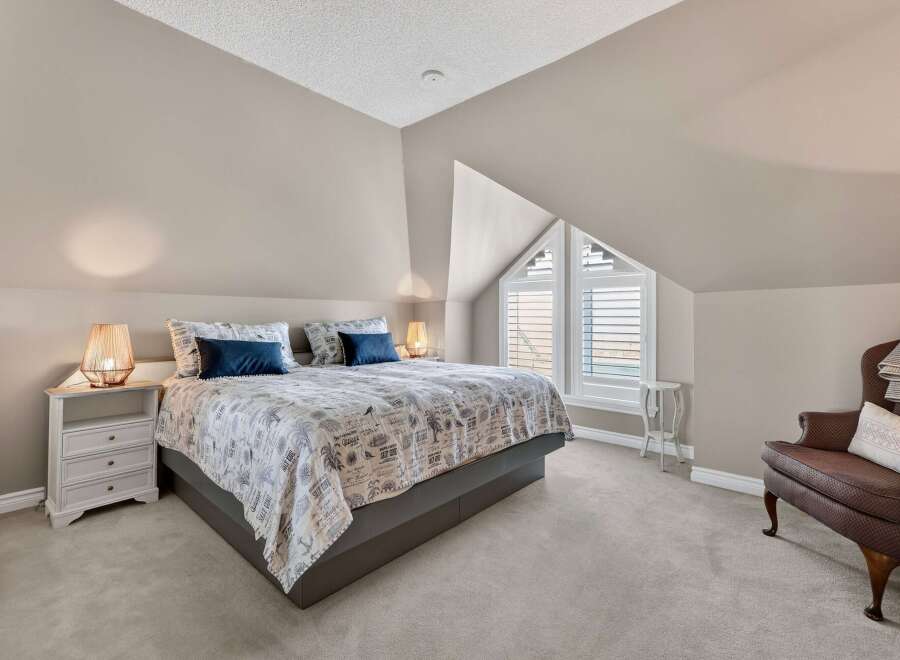 This stunning bedroom boasts a unique architectural design with a sloped ceiling and a striking triangular window.