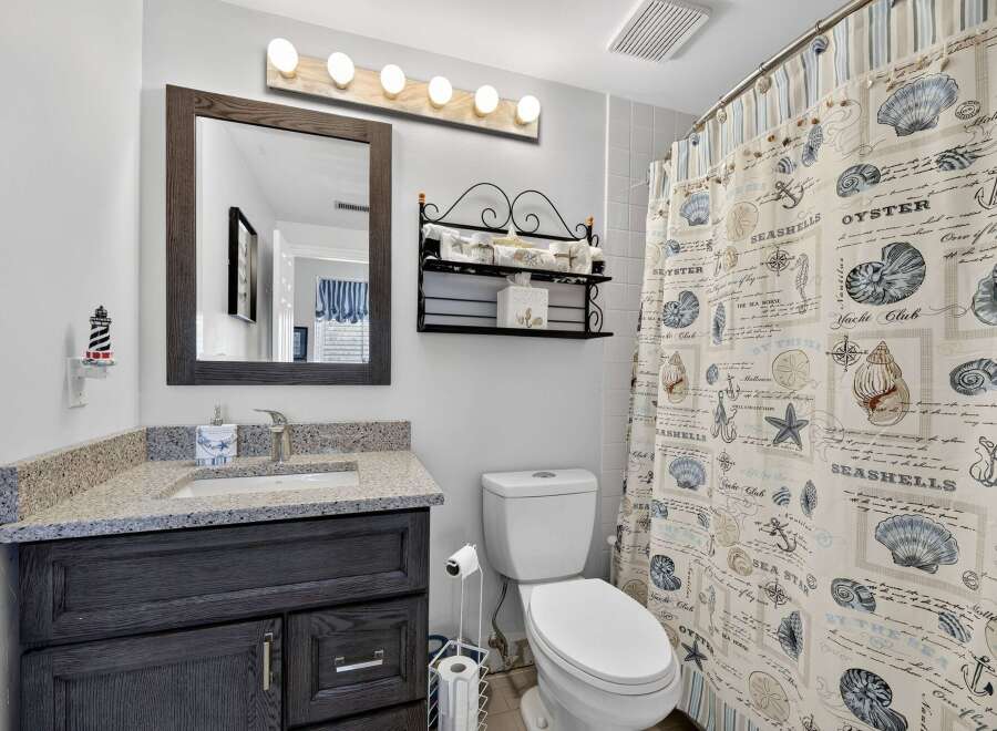 This charming bathroom features a coastal theme with a seashell-printed shower curtain and nautical accents.