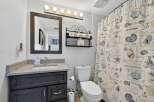 This charming bathroom features a coastal theme with a seashell-printed shower curtain and nautical accents.