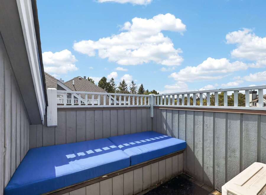 Enjoy the outdoors from this charming balcony! This space features a comfortable blue cushion, perfect for relaxing and soaking up the sun.
