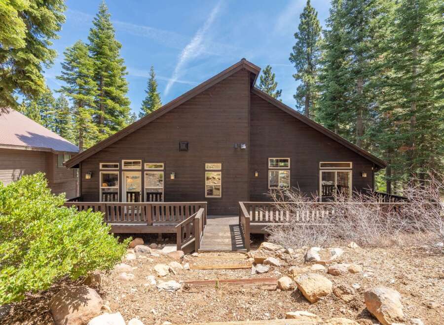 Nestled amidst towering trees, this stunning property boasts a dark wood exterior and a welcoming deck.