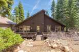 Nestled amidst towering trees, this stunning property boasts a dark wood exterior and a welcoming deck.