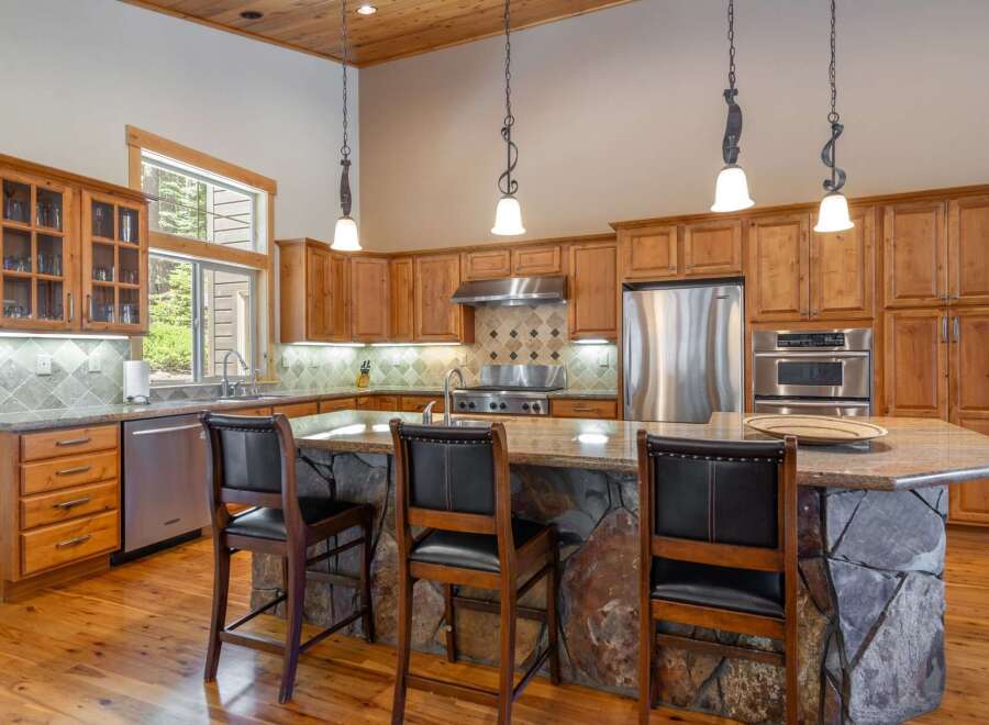 This stunning kitchen boasts custom cabinetry, stainless steel appliances, and a spacious island with a stone base.