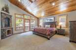 Step into luxury with this stunning bedroom featuring a cozy fireplace and a rustic wooden ceiling.
