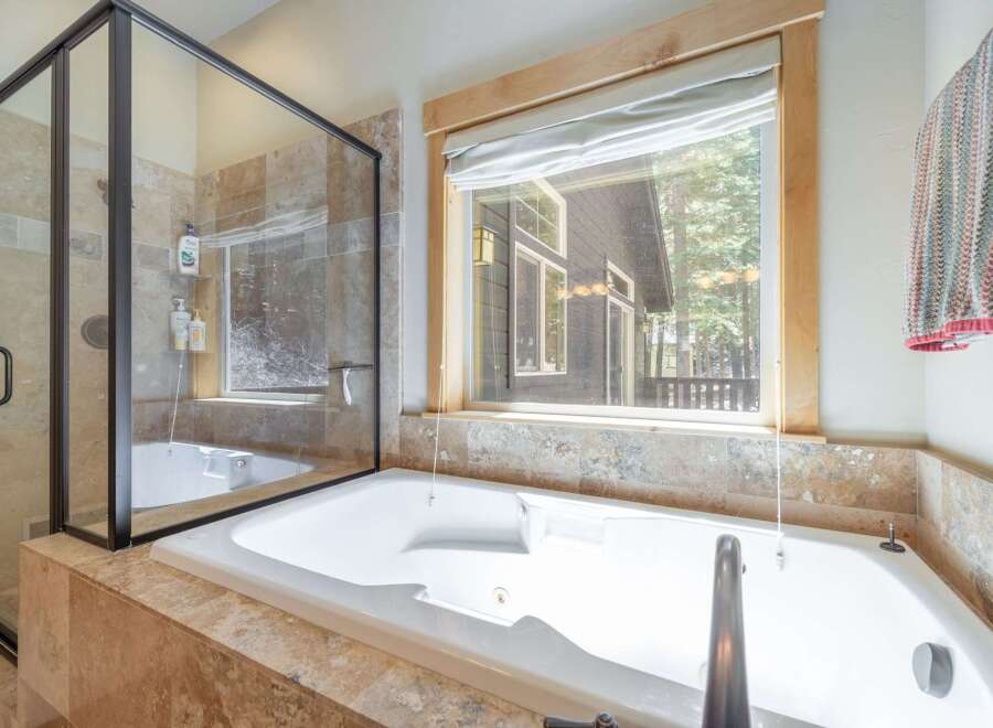 Enjoy a luxurious soak in this stunning bathroom! Featuring a modern tub, a separate shower, and a large window with a view, this space is perfect for relaxation.