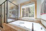 Enjoy a luxurious soak in this stunning bathroom! Featuring a modern tub, a separate shower, and a large window with a view, this space is perfect for relaxation.