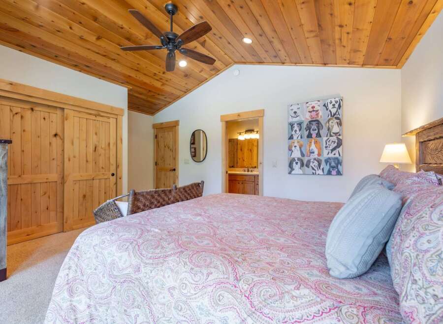 This charming bedroom features a cozy wooden ceiling and a comfortable bed with a unique patterned comforter.