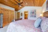 This charming bedroom features a cozy wooden ceiling and a comfortable bed with a unique patterned comforter.