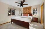 This cozy bedroom features a beautiful wooden bed frame and a stylish ceiling fan.