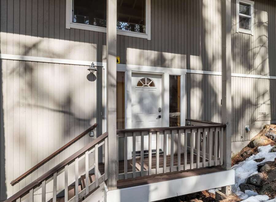 This charming property boasts a welcoming entrance with a covered porch and a stylish white door.