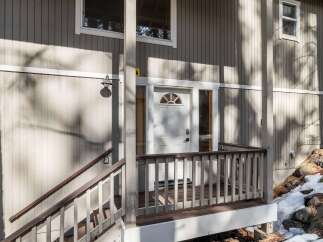 This charming property boasts a welcoming entrance with a covered porch and a stylish white door.