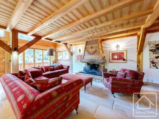 Experience luxury living in this stunning property, featuring a cozy living room with a fireplace and elegant red sofas.
