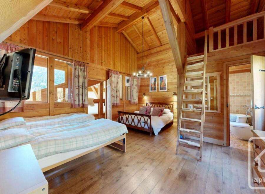 Step into this charming chalet-style bedroom, boasting a warm and inviting ambiance with its wooden walls and floors.