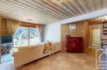 Discover the charm of this stunning property, featuring a cozy living room with a beautiful wooden ceiling and large windows that offer breathtaking views of the surrounding mountains.