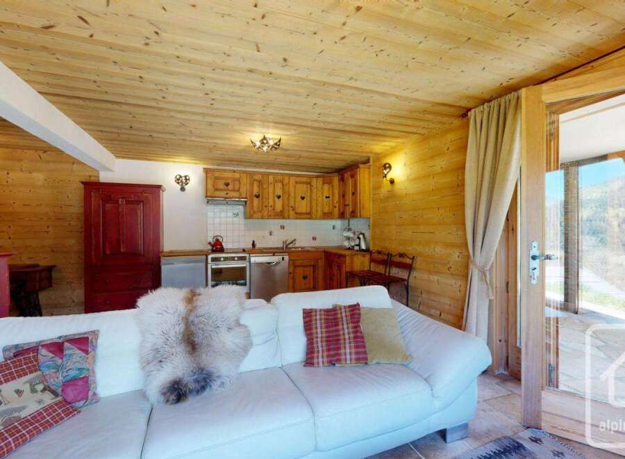 Experience the charm of this cozy alpine property, featuring a warm wooden interior and a comfortable living space.