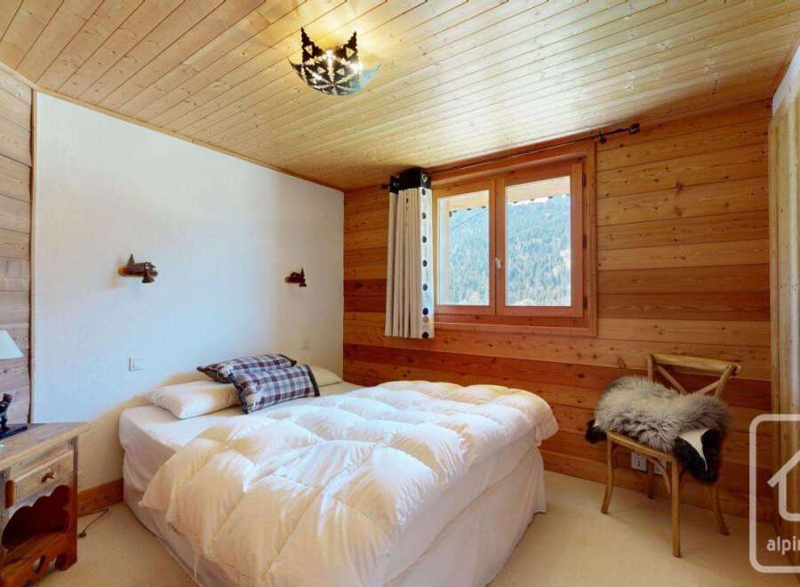 Discover the charm of this cozy bedroom, featuring a warm wooden interior and a comfortable bed.