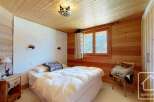 Discover the charm of this cozy bedroom, featuring a warm wooden interior and a comfortable bed.
