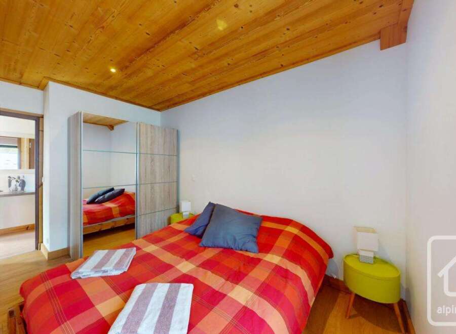 Discover this charming bedroom featuring a cozy bed with a vibrant red and orange plaid comforter.