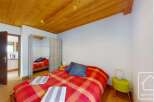 Discover this charming bedroom featuring a cozy bed with a vibrant red and orange plaid comforter.