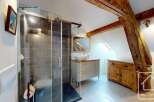 Discover this stunning bathroom featuring a modern glass shower, elegant vanity, and a touch of rustic charm with exposed wooden beams.