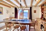 This charming dining room boasts a rustic aesthetic with exposed wooden beams and a large wooden dining table.