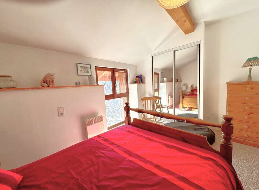 Discover this charming bedroom featuring a cozy bed with a vibrant red comforter.