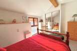 Discover this charming bedroom featuring a cozy bed with a vibrant red comforter.
