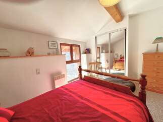 Discover this charming bedroom featuring a cozy bed with a vibrant red comforter.