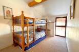 This charming property features a cozy bedroom with a wooden bunk bed, perfect for accommodating guests or family.