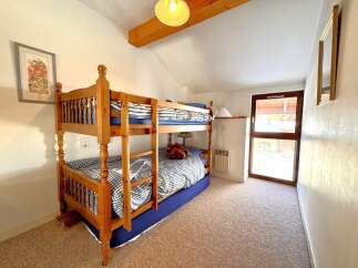 This charming property features a cozy bedroom with a wooden bunk bed, perfect for accommodating guests or family.
