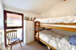 This cozy bedroom features a charming wooden bunk bed, perfect for accommodating guests or family members.