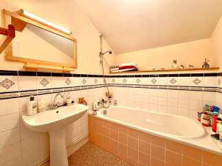 This charming bathroom features a classic design with a pedestal sink and a bathtub.
