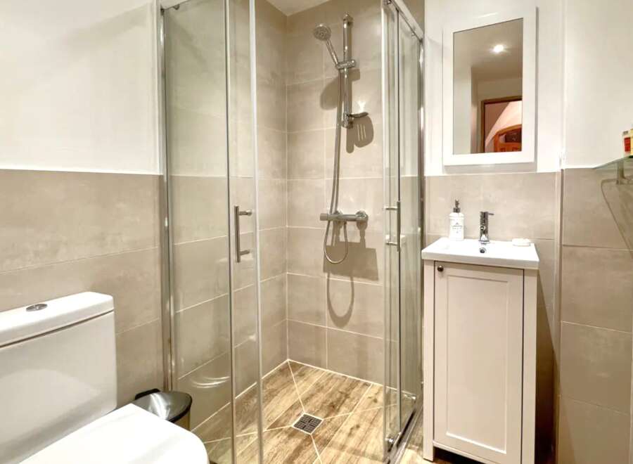 Step into this modern bathroom featuring a sleek glass shower enclosure, perfect for a refreshing start to your day.