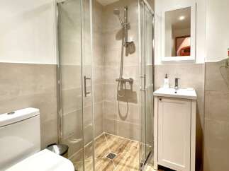 Step into this modern bathroom featuring a sleek glass shower enclosure, perfect for a refreshing start to your day.