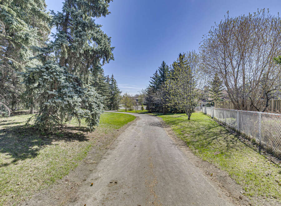 Discover the tranquility of this property, featuring a serene pathway winding through lush greenery.