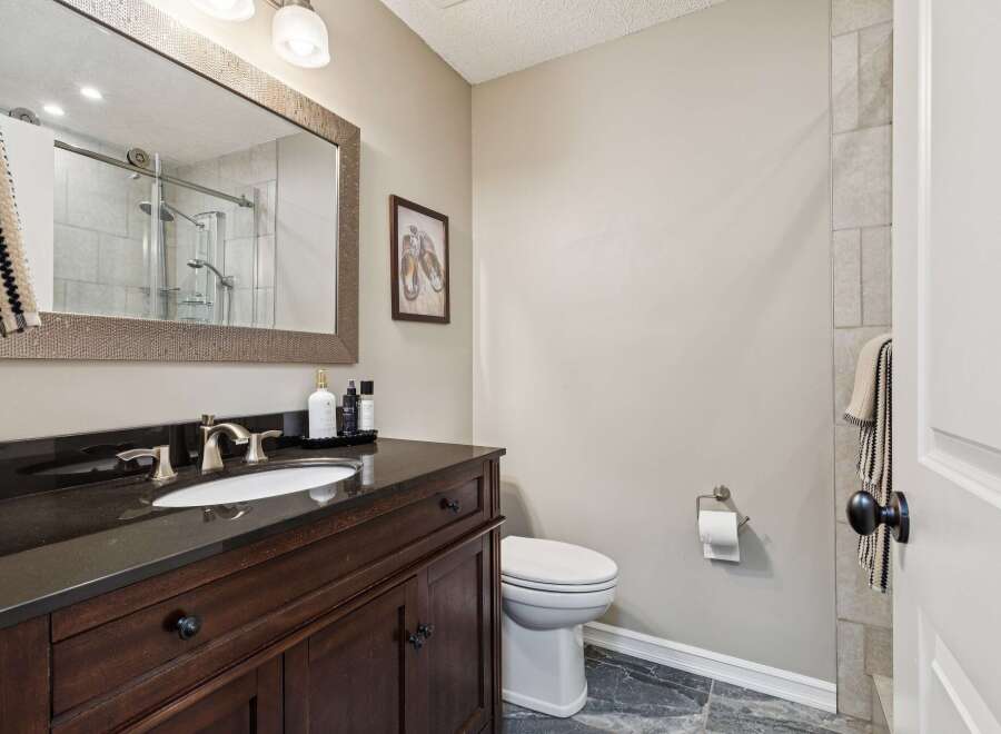 This stunning bathroom boasts a sleek, modern design with a dark wood vanity and a contrasting black countertop.
