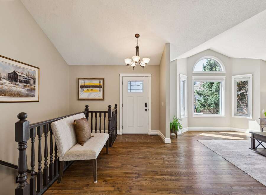 Step into this inviting entryway, showcasing beautiful hardwood floors and a welcoming bench.