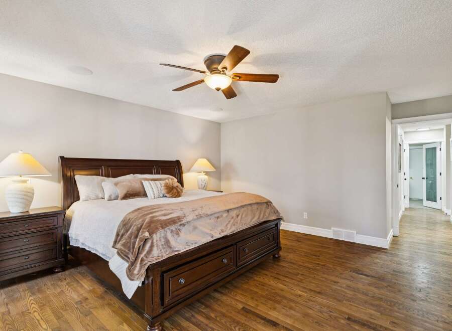 Step into luxury with this stunning bedroom featuring a grand, dark wood bed frame and matching nightstands.
